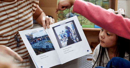 Educator reading a Geodes book to students and a student pointing at the book
