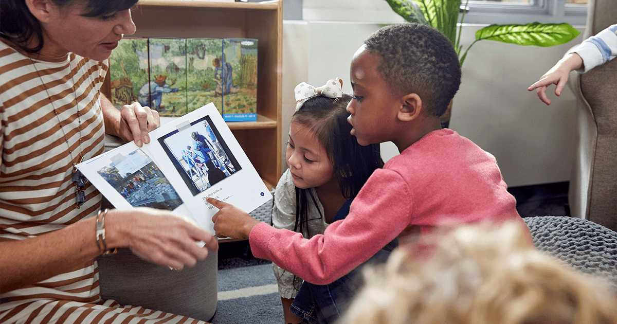 Teacher showing a picture book to young children in a classroom setting, engaging students in early literacy and reading activities.
