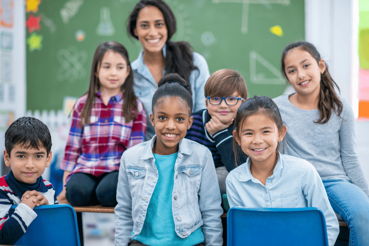 Teacher with a group of students and a blackboard in the background